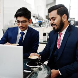two-indian-business-man-suits-sitting-office-cafe-looking-laptop-drinking-coffee_627829-1513
